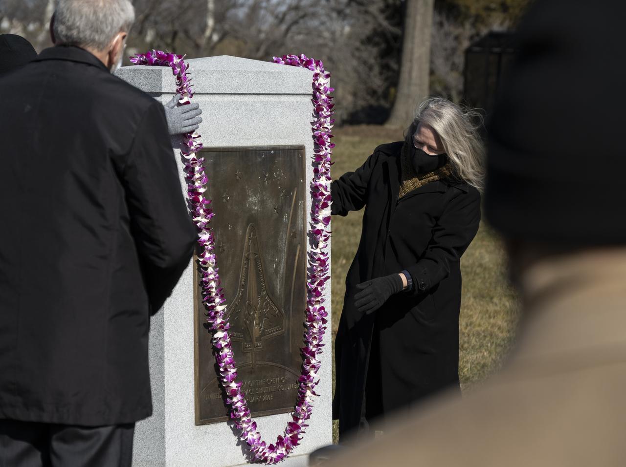 Acting NASA Administrator Steve Jurczyk, left, watches as McCool Family Representative Kristy Carroll places a lei on the Space Shuttle Columbia Memorial during a ceremony that was part of NASA's Day of Remembrance, Thursday, Jan. 28, 2021, at Arlington National Cemetery in Arlington, Va. Wreaths were laid in memory of those men and women who lost their lives in the quest for space exploration.  Photo Credit: (NASA/Bill Ingalls)