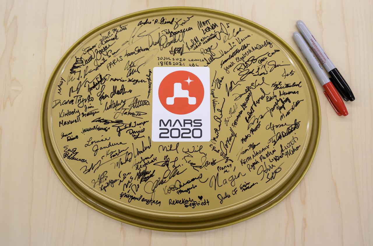 A serving tray with signatures from the NASA Perseverance Mars rover team is seen in mission control, Thursday, Feb. 18, 2021, at NASA's Jet Propulsion Laboratory in Pasadena, California. A key objective for Perseverance’s mission on Mars is astrobiology, including the search for signs of ancient microbial life. The rover will characterize the planet’s geology and past climate, pave the way for human exploration of the Red Planet, and be the first mission to collect and cache Martian rock and regolith. Photo Credit: (NASA/Bill Ingalls)