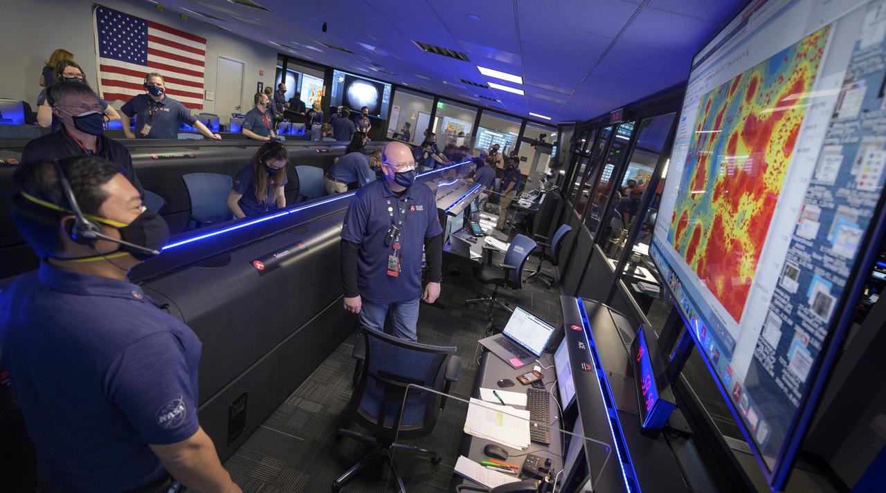 Members of NASA’s Perseverance Mars rover team watch in mission control as the first images arrive moments after the spacecraft successfully touched down on Mars, Thursday, Feb. 18, 2021, at NASA's Jet Propulsion Laboratory in Pasadena, California. A key objective for Perseverance’s mission on Mars is astrobiology, including the search for signs of ancient microbial life. The rover will characterize the planet’s geology and past climate, pave the way for human exploration of the Red Planet, and be the first mission to collect and cache Martian rock and regolith. Photo Credit: (NASA/Bill Ingalls)