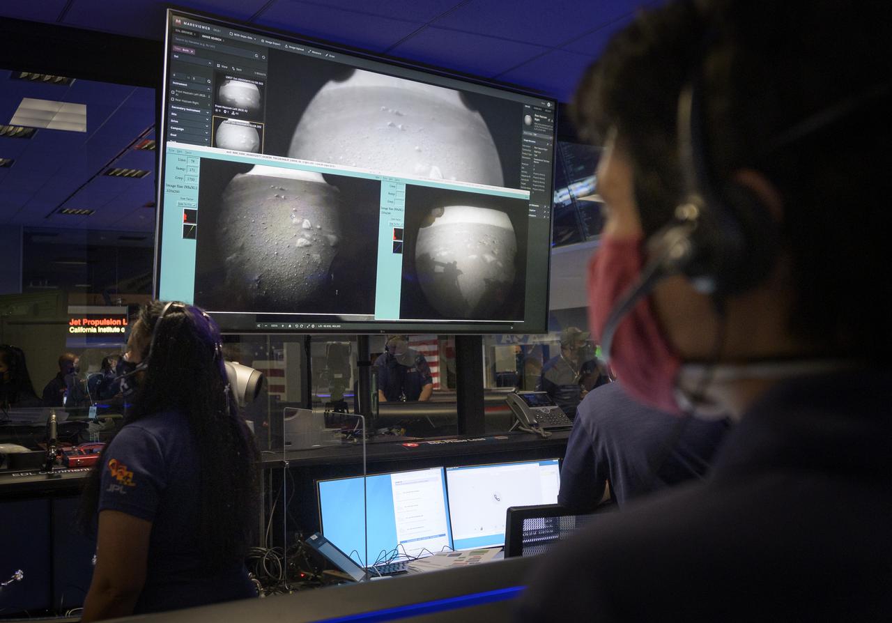 Members of NASA’s Perseverance Mars rover team watch in mission control as the first images arrive moments after the spacecraft successfully touched down on Mars, Thursday, Feb. 18, 2021, at NASA's Jet Propulsion Laboratory in Pasadena, California. A key objective for Perseverance’s mission on Mars is astrobiology, including the search for signs of ancient microbial life. The rover will characterize the planet’s geology and past climate, pave the way for human exploration of the Red Planet, and be the first mission to collect and cache Martian rock and regolith. Photo Credit: (NASA/Bill Ingalls)