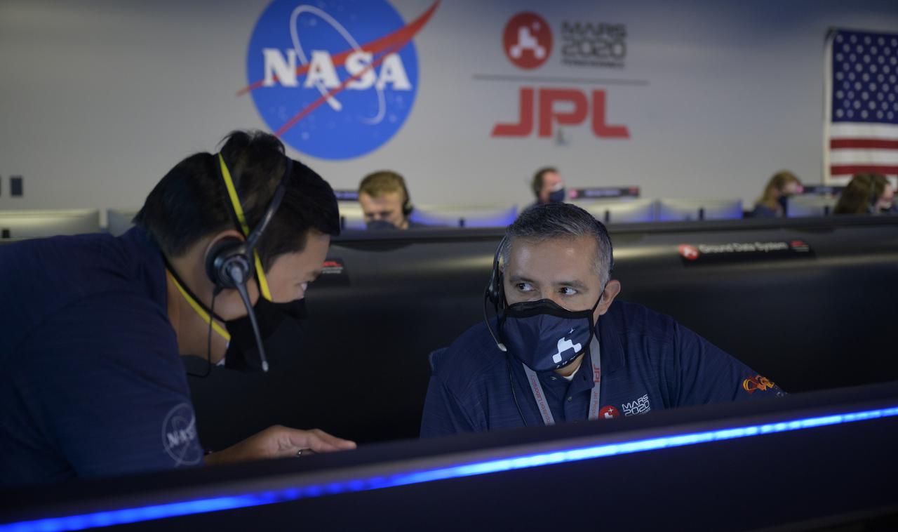 Members of NASA’s Perseverance Mars rover team confer and study data on monitors in mission control, Thursday, Feb. 18, 2021, at NASA's Jet Propulsion Laboratory in Pasadena, California. A key objective for Perseverance’s mission on Mars is astrobiology, including the search for signs of ancient microbial life. The rover will characterize the planet’s geology and past climate, pave the way for human exploration of the Red Planet, and be the first mission to collect and cache Martian rock and regolith. Photo Credit: (NASA/Bill Ingalls)