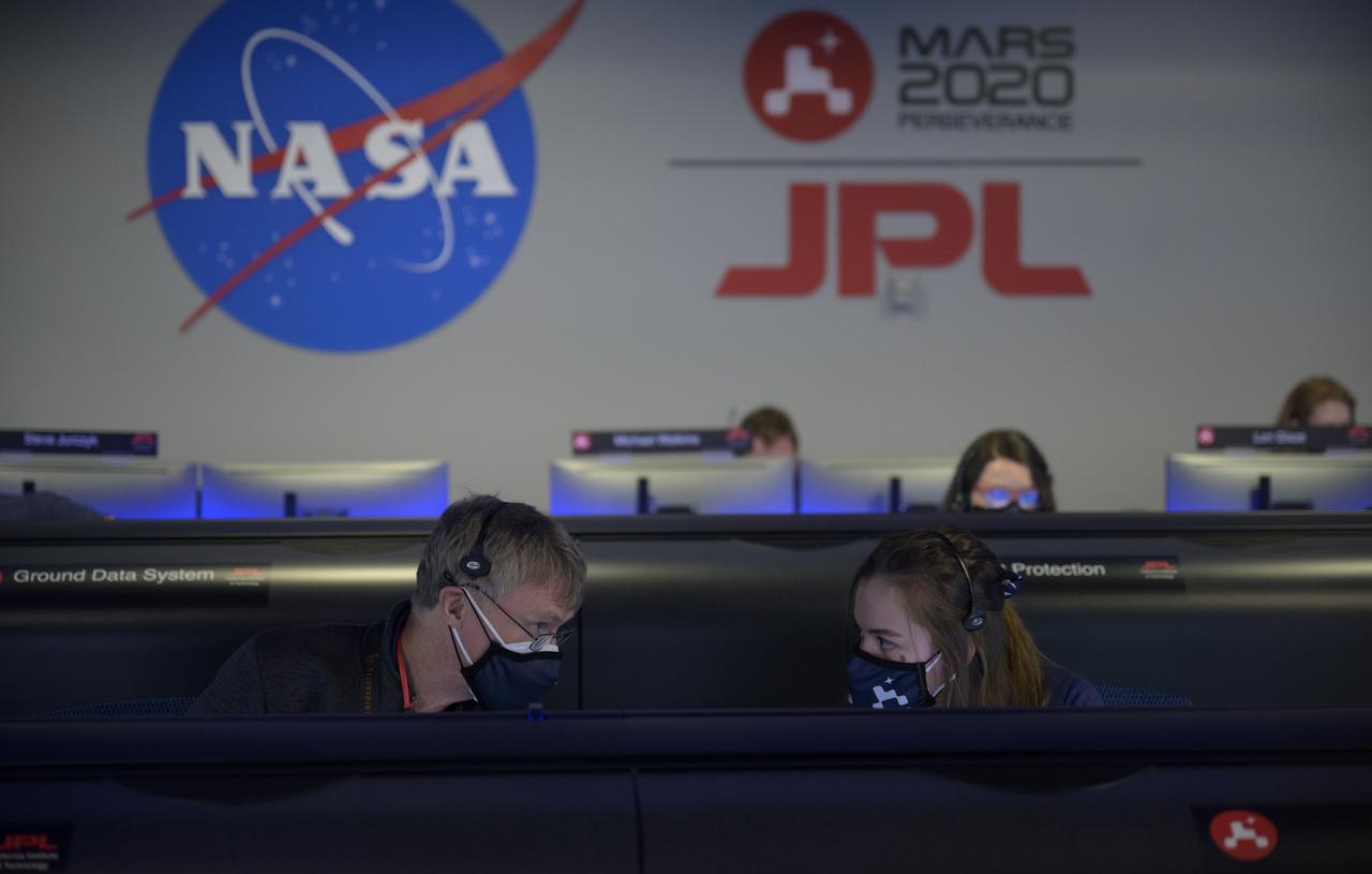 Members of NASA’s Perseverance Mars rover team confer and study data on monitors in mission control, Thursday, Feb. 18, 2021, at NASA's Jet Propulsion Laboratory in Pasadena, California. A key objective for Perseverance’s mission on Mars is astrobiology, including the search for signs of ancient microbial life. The rover will characterize the planet’s geology and past climate, pave the way for human exploration of the Red Planet, and be the first mission to collect and cache Martian rock and regolith. Photo Credit: (NASA/Bill Ingalls)