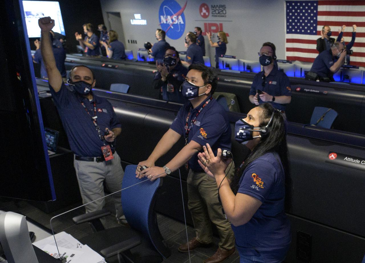 Members of NASA’s Perseverance Mars rover team watch in mission control as the first images arrive moments after the spacecraft successfully touched down on Mars, Thursday, Feb. 18, 2021, at NASA's Jet Propulsion Laboratory in Pasadena, California. A key objective for Perseverance’s mission on Mars is astrobiology, including the search for signs of ancient microbial life. The rover will characterize the planet’s geology and past climate, pave the way for human exploration of the Red Planet, and be the first mission to collect and cache Martian rock and regolith. Photo Credit: (NASA/Bill Ingalls)