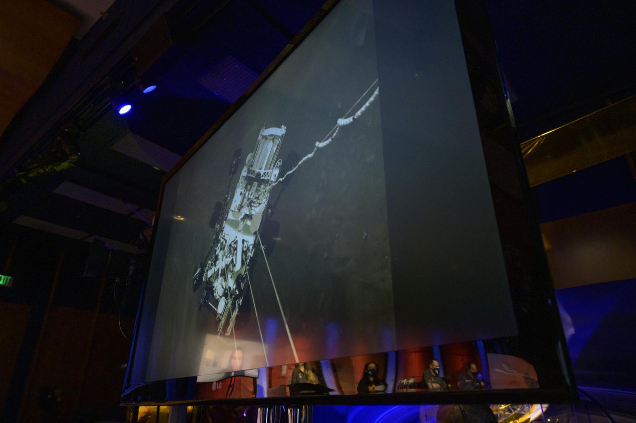 A high-resolution still image captured from cameras aboard the descent stage as NASA’s Perseverance rover touched down on Mars Feb. 18, 2021, is shown during a NASA Perseverance rover initial surface checkout briefing, Friday Feb. 19, 2021, at NASA's Jet Propulsion Laboratory in Pasadena, California. A key objective for Perseverance’s mission on Mars is astrobiology, including the search for signs of ancient microbial life. The rover will characterize the planet’s geology and past climate, pave the way for human exploration of the Red Planet, and be the first mission to collect and cache Martian rock and regolith. Photo Credit: (NASA/Bill Ingalls)