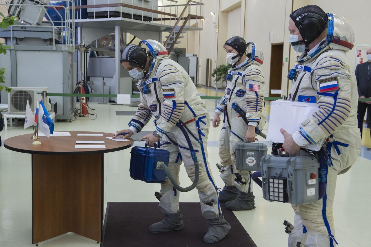 Expedition 65 backup crew member Anton Shkaplerov of Roscosmos, signs in for Soyuz qualification exams as crew mates Oleg Artemyev of Roscosmos, right, and Anne McClain of NASA look on, Monday, March 22, 2021 at the Gagarin Cosmonaut Training Center (GCTC) in Star City, Russia, in advance of the Expedition 65 launch April 9 from Baikonur Cosmodrome in Kazakhstan to the International Space Station. Photo Credit: (NASA/GCTC/Irina Spector)