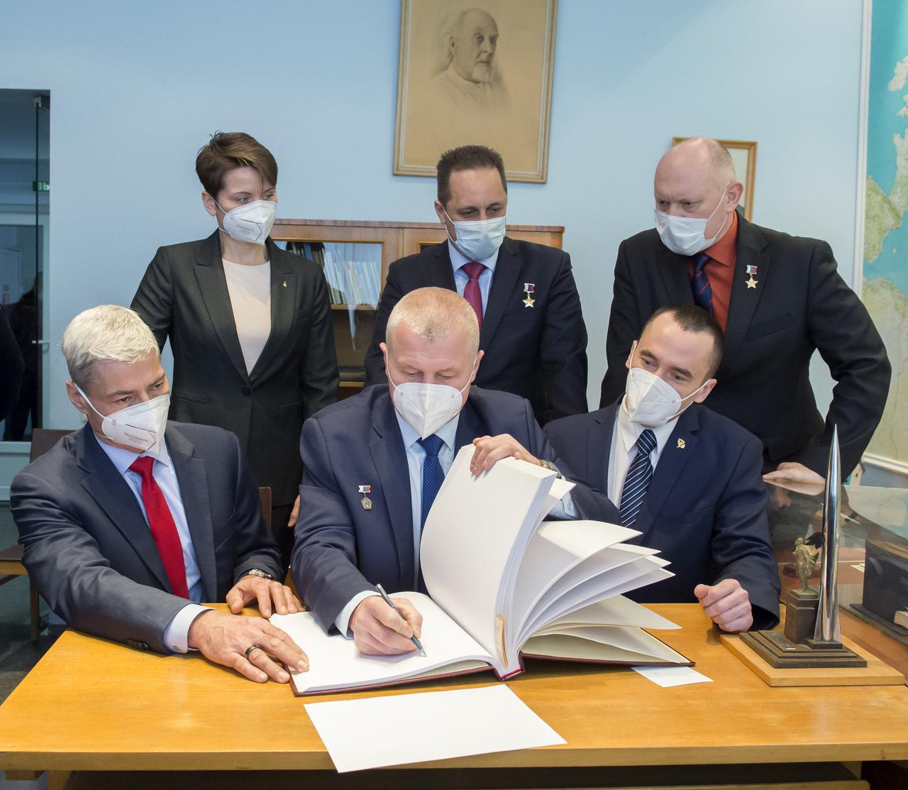Expedition 65 prime crew member, Oleg Novitskiy of Roscosmos signs a guest book at the "Memorial working study of Yuri Gagarin" at the Gagarin Cosmonaut Training Center (GCTC), as his crew mates watch, Wednesday, March 24, 2021 in Star City, Russia. The memorial study represents Gagarin's working study in the way it was abandoned by Gagarin on March 27, 1968 before leaving for the airfield for training flight that became his last. Photo Credit: (NASA/GCTC/Irina Spector)