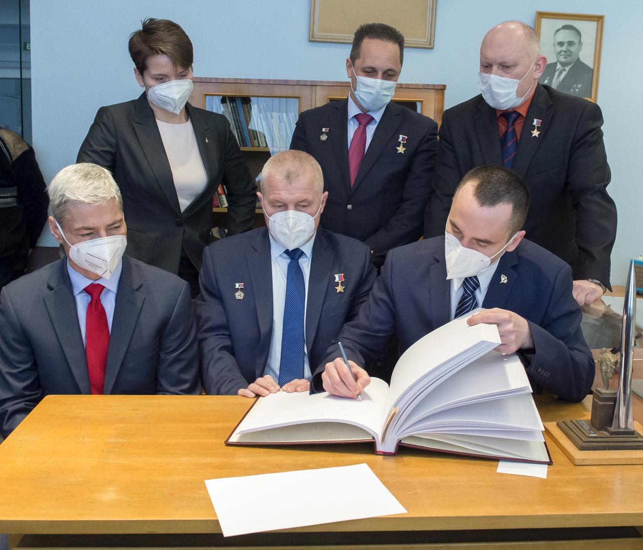 Expedition 65 prime crew member, Pyotr Dubrov of Roscosmos signs a guest book at the "Memorial working study of Yuri Gagarin" at the Gagarin Cosmonaut Training Center (GCTC), as his crew mates watch, Wednesday, March 24, 2021 in Star City, Russia. The memorial study represents Gagarin's working study in the way it was abandoned by Gagarin on March 27, 1968 before leaving for the airfield for training flight that became his last. Photo Credit: (NASA/GCTC/Irina Spector)