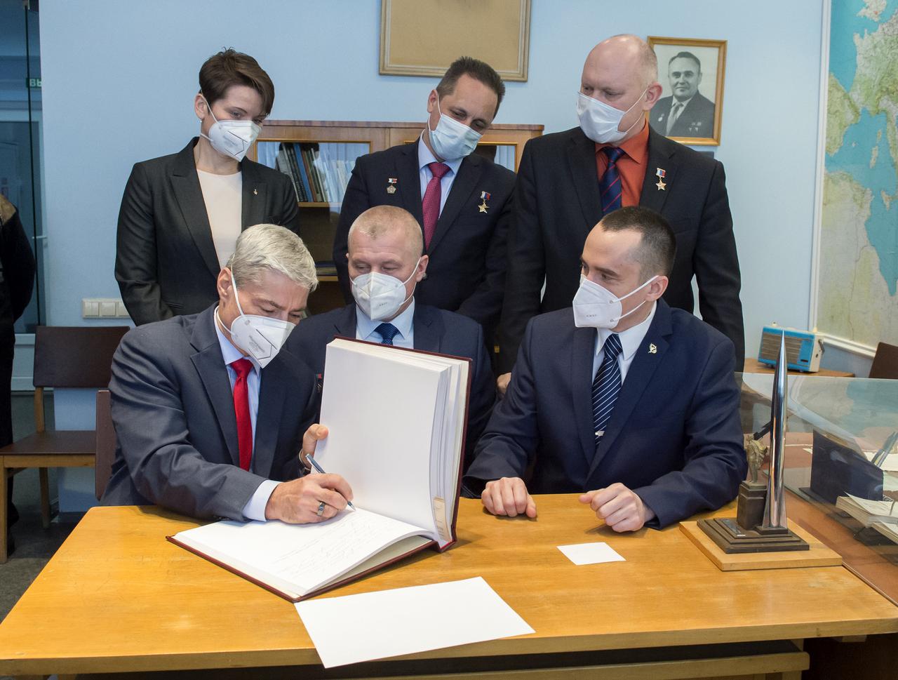 Expedition 65 prime crew member, Mark Vande Hei of NASA signs a guest book at the "Memorial working study of Yuri Gagarin" at the Gagarin Cosmonaut Training Center (GCTC), as his crew mates watch, Wednesday, March 24, 2021 in Star City, Russia. The memorial study represents Gagarin's working study in the way it was abandoned by Gagarin on March 27, 1968 before leaving for the airfield for training flight that became his last. Photo Credit: (NASA/GCTC/Irina Spector)