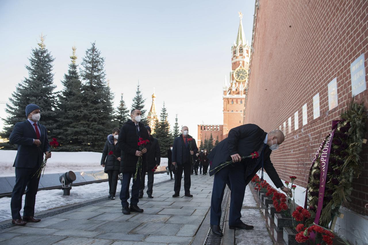 Expedition 65 prime crew members NASA astronaut Mark Vande Hei, left, and Russian cosmonaut Pyotr Dubrov of Roscosmos, center, watch as Russian cosmonaut Oleg Novitskiy of Roscosmos lays flowers at the site where Russian space icons are interred as part of traditional pre-launch ceremonies, Wednesday, March 24, 2021, at Red Square in Moscow. Photo Credit: (NASA/GCTC/Andrey Shelepin)