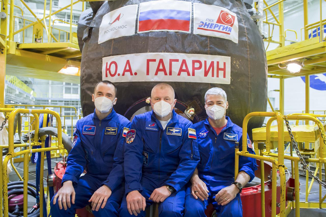 Expedition 65 prime crew members Pyotr Dubrov of Roscosmos, left, Oleg Novitskiy of Roscosmos, center, and NASA astronaut Mark Vande Hei, pose for a photo in front of the Soyuz MS-18 spacecraft, named after the first human to journey into space, Yuri Gagarin, during a fit check Saturday, March 27, 2021 at the Baikonur Cosmodrome in Kazakhstan. They are scheduled to launch on a Soyuz rocket April 9. Photo Credit: (NASA/GCTC/Irina Spector)