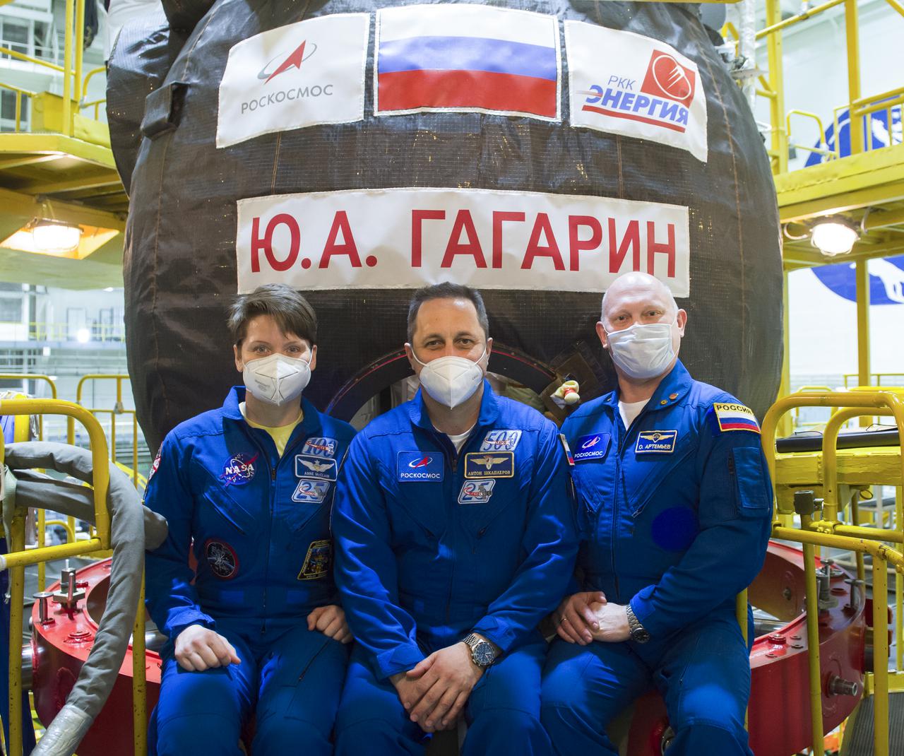 Expedition 65 backup crew members NASA astronaut Anne McClain, Russian cosmonauts Anton Shkaplerov of Roscosmos, center, and Oleg Artemyev of Roscosmos, pose for a photo in front of the Soyuz MS-18 spacecraft, named after the first human to journey into space, Yuri Gagarin, during a fit check Saturday, March 27, 2021 at the Baikonur Cosmodrome in Kazakhstan. The prime crew is scheduled to launch on a Soyuz rocket April 9. Photo Credit: (NASA/GCTC/Irina Spector)
