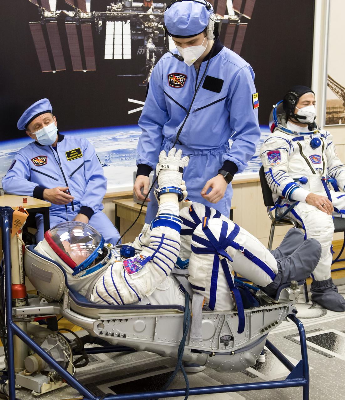 Expedition 65 prime crew member Oleg Novitskiy of Roscosmos has his Sokol suit pressure checked while fellow crew mates, NASA astronaut Mark Vande Hei, right, and Russian cosmonaut Pyotr Dubrov of Roscosmos look on, during a fit check to prepare for launch, Saturday, March 27, 2021 at the Baikonur Cosmodrome in Kazakhstan. They are scheduled to launch on a Soyuz rocket April 9. Photo Credit: (NASA/GCTC/Irina Spector)
