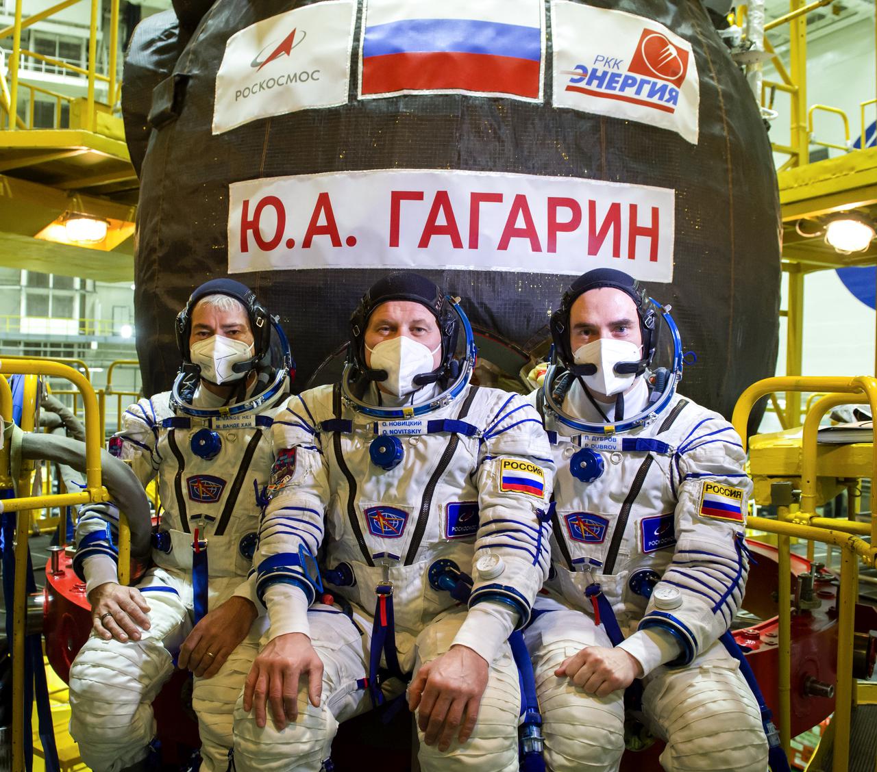 Expedition 65 prime crew member NASA astronaut Mark Vande Hei, left, and Russian cosmonauts Oleg Novitskiy of Roscosmos center, and Pyotr Dubrov of Roscosmos, right, pose for a photo in front of the Soyuz MS-18 spacecraft, named after the first human to journey into space, Yuri Gagarin, after their fit check, Saturday, March 27, 2021 at the Baikonur Cosmodrome in Kazakhstan. They are scheduled to launch on a Soyuz rocket April 9. Photo Credit: (NASA/GCTC/Irina Spector)
