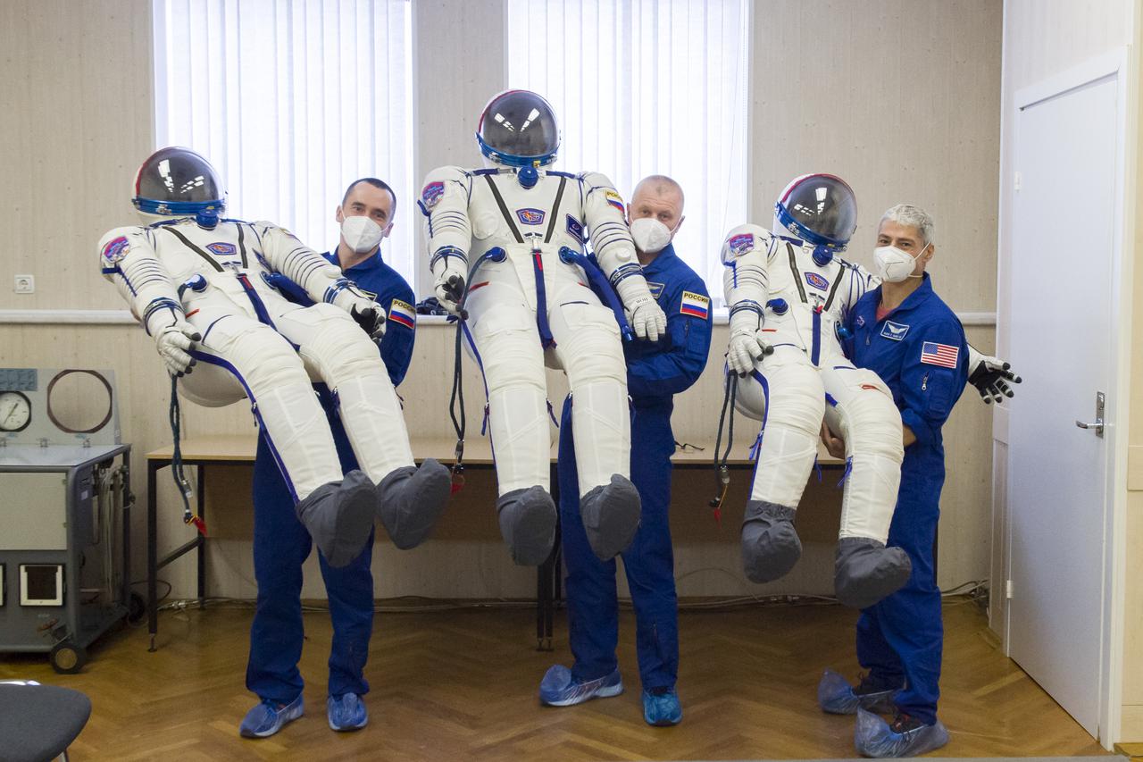 Expedition 65 prime crew members Pyotr Dubrov of Roscosmos, left, Oleg Novitskiy of Roscosmos, center, and NASA astronaut Mark Vande Hei, right, are seen holding their Sokol suits during a fit check, Saturday, March 27, 2021 at the Baikonur Cosmodrome in Kazakhstan. They are scheduled to launch on a Soyuz rocket April 9. Photo Credit: (NASA/GCTC/Irina Spector)