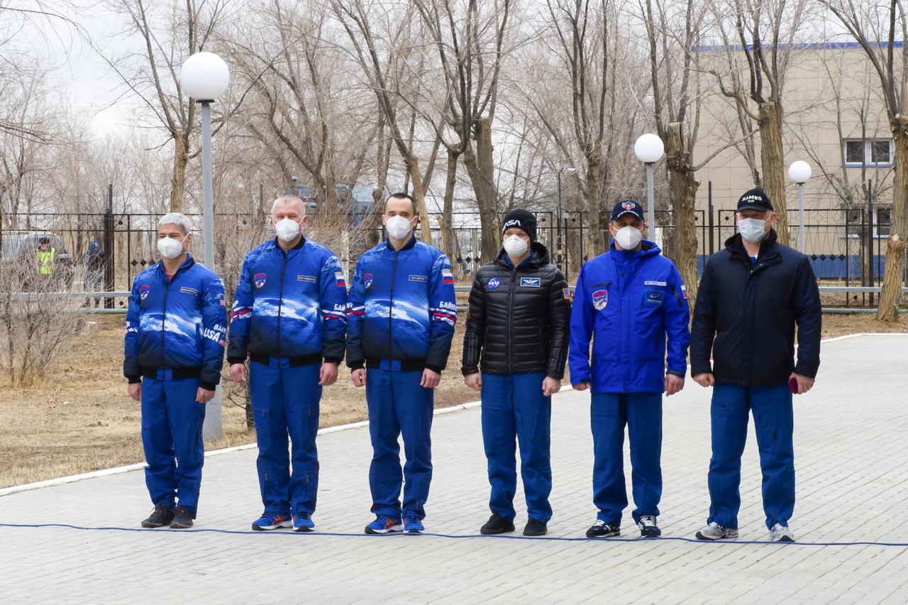 Expedition 65 prime and backup crew members rare seen just prior to raising the flags of Russia, the United States, and Kazakhstan, Sunday, March 28, 2021, in traditional ceremonies outside the Cosmonaut Hotel in Baikonur, Kazakhstan. From left to right, Expedition 65 prime crew members, NASA astronaut Mark Vande Hei, Russian cosmonauts Oleg Novitskiy of Roscosmos and Pyotr Dubrov of Roscosmos, and Expedition 65 backup crew members NASA astronaut Anne McClain, and Russian cosmonauts Anton Shkaplerov of Roscosmos, and Oleg Artemyev of Roscosmos. The prime crew is scheduled to launch to the International Space Station on a Soyuz rocket April 9. Photo Credit: (NASA/GCTC/Irina Spector)