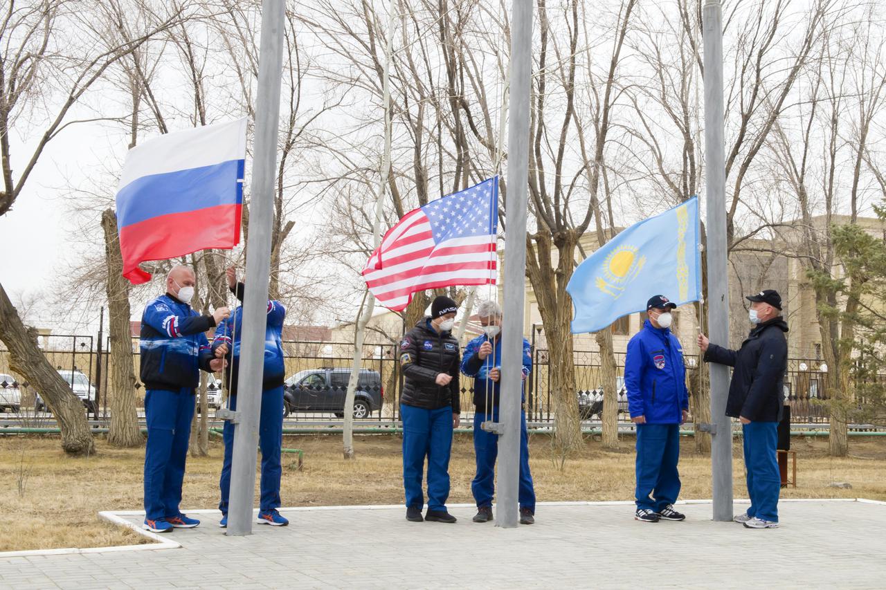 Expedition 65 prime and backup crew members raise the flags of Russia, the United States, and Kazakhstan, Sunday, March 28, 2021, in traditional ceremonies outside the Cosmonaut Hotel in Baikonur, Kazakhstan. From left to right, Expedition 65 prime crew member Oleg Novitskiy of Roscosmos and backup crew member Pyotr Dubrov of Roscosmos, Expedition 65 backup crew member, NASA astronaut Anne McClain and prime crew NASA astronaut Mark Vande Hei, and Expedition 65 backup crew cosmonaut Anton Shkaplerov of Roscosmos and prime crew cosmonaut Oleg Artemyev of Roscosmos. The prime crew is scheduled to launch to the International Space Station on a Soyuz rocket April 9. Photo Credit: (NASA/GCTC/Irina Spector)