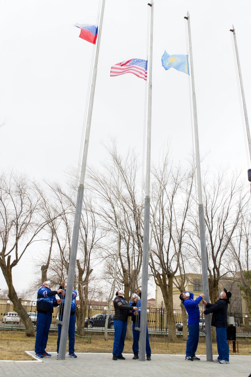 Expedition 65 prime and backup crew members raise the flags of Russia, the United States, and Kazakhstan, Sunday, March 28, 2021, in traditional ceremonies outside the Cosmonaut Hotel in Baikonur, Kazakhstan. From left to right, Expedition 65 prime crew member Oleg Novitskiy of Roscosmos and backup crew member Pyotr Dubrov of Roscosmos, Expedition 65 backup crew member, NASA astronaut Anne McClain, and prime crew member NASA astronaut Mark Vande Hei, and Expedition 65 backup crew cosmonaut Anton Shkaplerov of Roscosmos and prime crew cosmonaut Oleg Artemyev of Roscosmos. The prime crew is scheduled to launch to the International Space Station on a Soyuz rocket April 9. Photo Credit: (NASA/GCTC/Irina Spector)