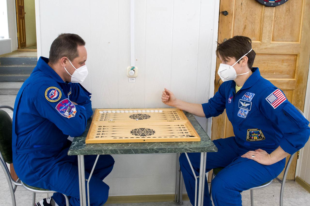 Expedition 65 backup crew member Russian cosmonaut Anton Shkaplerov of Roscosmos, left, plays a game of backgammon with NASA astronaut Anne McClain, Saturday, April 3, 2021, at the Cosmonaut Hotel in Baikonur, Kazakhstan. The prime crew, NASA astronaut Mark Vande Hei, and Russian cosmonauts Oleg Novitskiy and Pyotr Dubrov of Roscosmos are scheduled to launch to the International Space Station aboard the Soyuz MS-18 spacecraft on April 9. Photo Credit: (NASA/GCTC/Irina Spector)