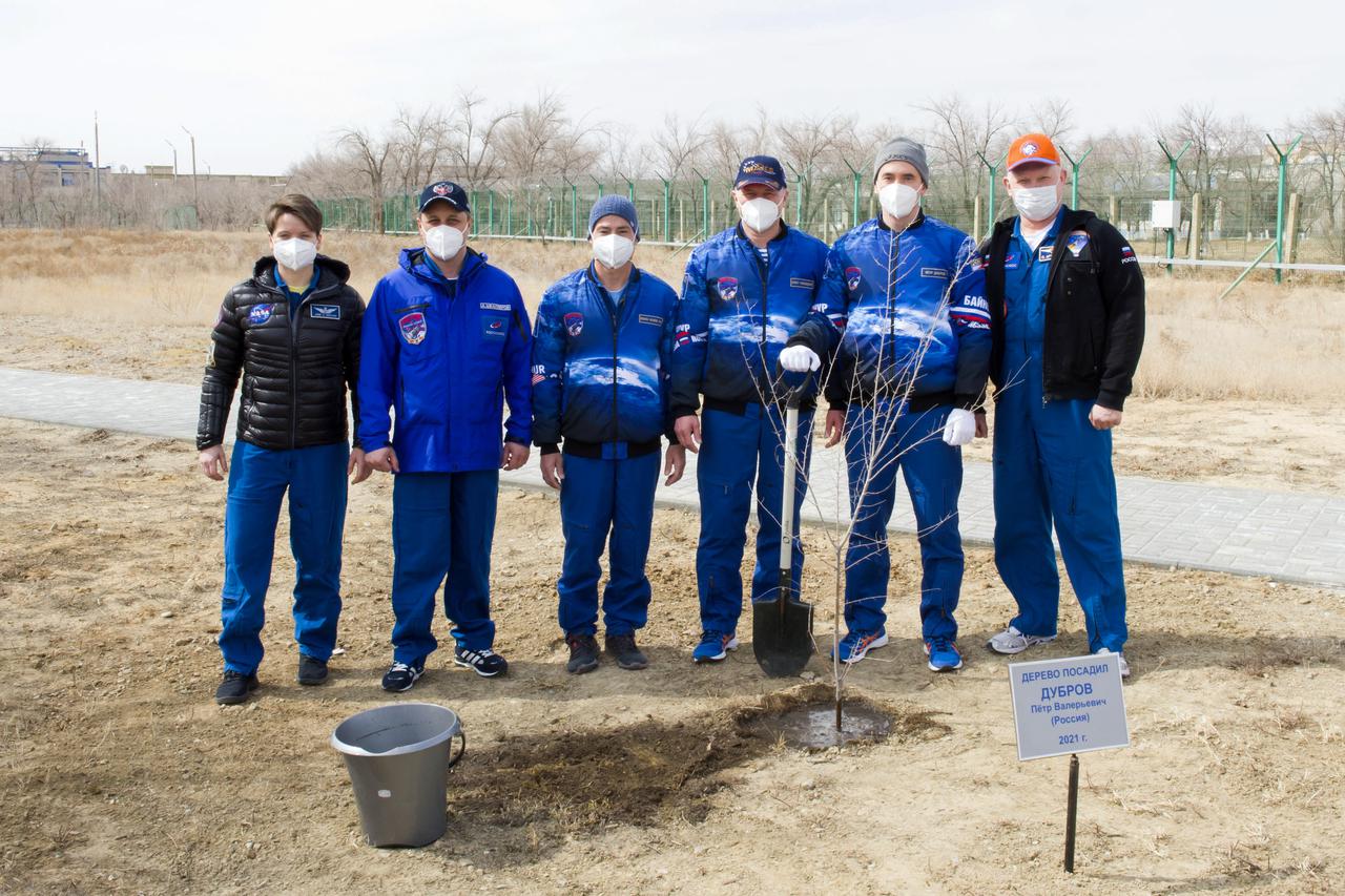 From left to right Expedition 65 backup crew members NASA astronaut Anne McClain and Russian cosmonaut Anton Shkaplerov of Roscosmos, and prime crew members NASA astronaut Mark Vande Hei, and Russian cosmonauts Pyotr Dubrov and Oleg Novitskiy of Roscosmos, and backup crew member Oleg Artemyev of Roscosmos pose for a photo after Dubrov planted a tree bearing his name as part of traditional pre-launch activities, Saturday, April 3, 2021, at the Cosmonaut Hotel in Baikonur, Kazakhstan. Vande Hei, Novitskiy and Dubrov are scheduled to launch to the International Space Station aboard the Soyuz MS-18 spacecraft on April 9. Photo Credit: (NASA/GCTC/Irina Spector)