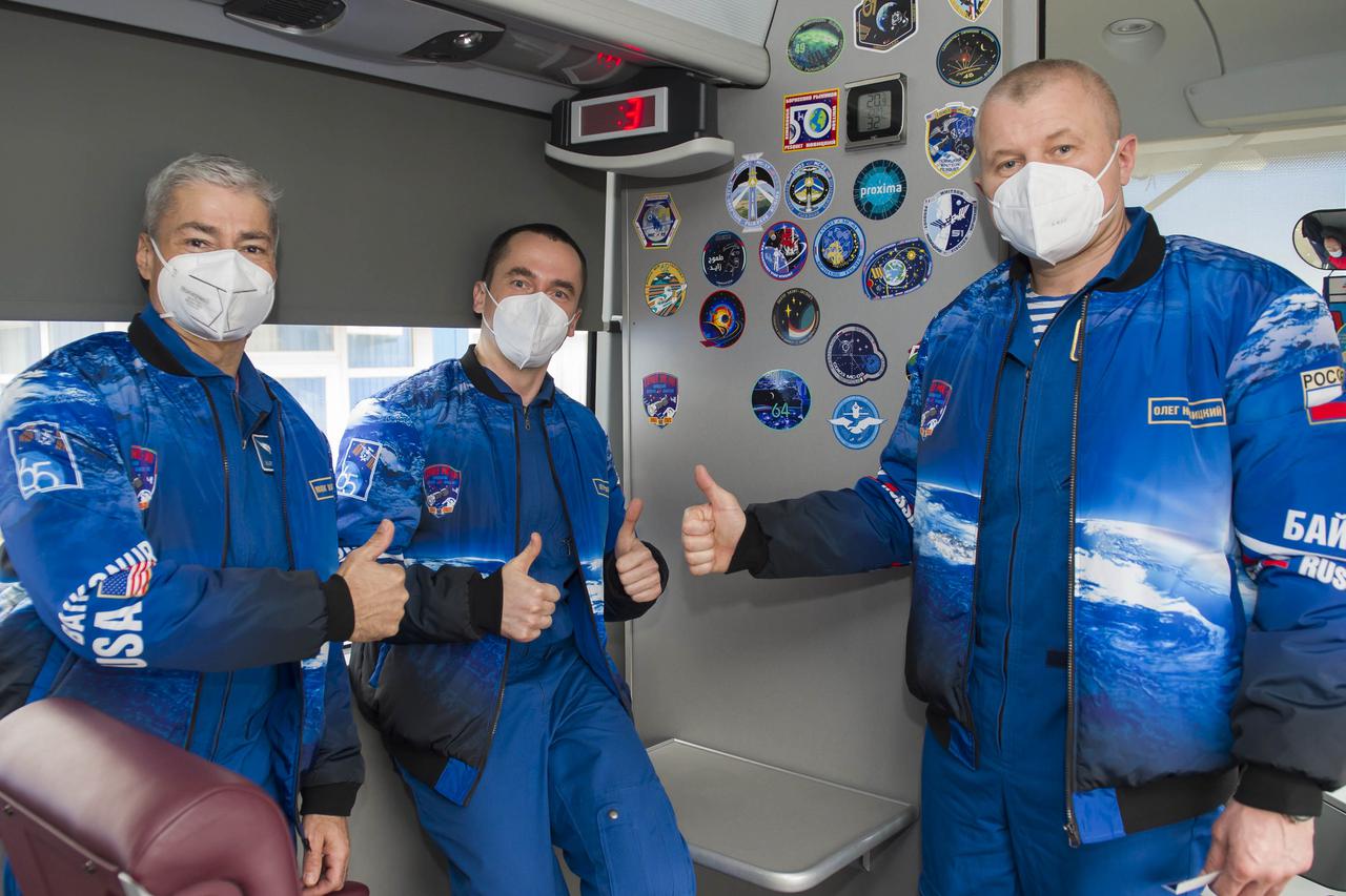 Expedition 65 prime crew members NASA astronaut Mark Vande Hei, left, Pyotr Dubrov, center, and Oleg Novitskiy of Roscosmos give a thumbs up in the bus that is taking them to their final fit check to prepare for launch, Sunday, April 4, 2021 at the Baikonur Cosmodrome in Kazakhstan. The trio are scheduled to launch to the International Space Station on a Soyuz rocket April 9. Photo Credit: (NASA/GCTC/Irina Spector)