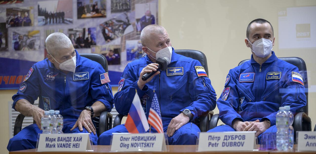 Expedition 65 NASA astronaut Mark Vande Hei, left, Roscosmos cosmonauts Oleg Novitskiy and Pyotr Dubrov, right, are seen in quarantine, behind glass, during a press conference, Thursday, April 8, 2021 a the Cosmonaut Hotel in Baikonur, Kazakhstan. The trio are scheduled to launch to the International Space Station aboard the Soyuz MS-18 spacecraft on April 9.  Photo Credit: (NASA/Bill Ingalls)