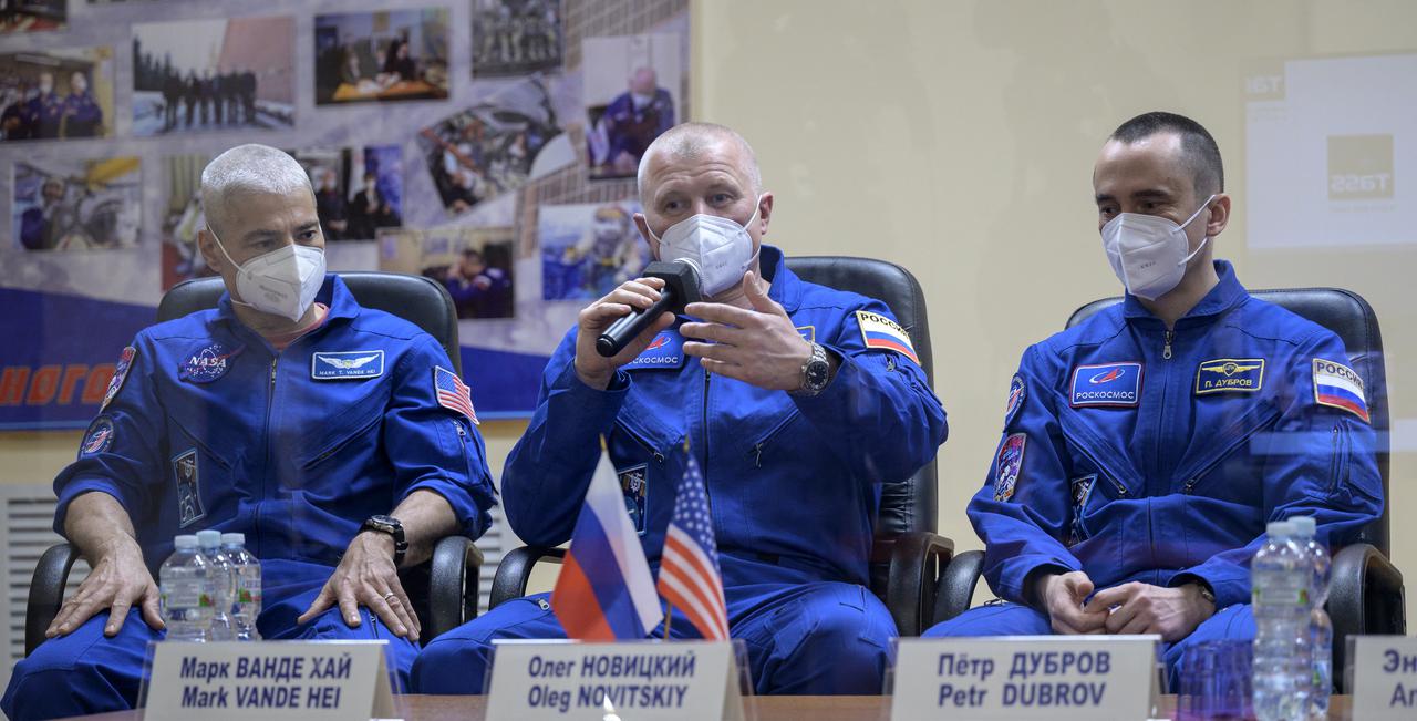 Expedition 65 NASA astronaut Mark Vande Hei, left, Roscosmos cosmonauts Oleg Novitskiy and Pyotr Dubrov, right, are seen in quarantine, behind glass, during a press conference, Thursday, April 8, 2021 a the Cosmonaut Hotel in Baikonur, Kazakhstan. The trio are scheduled to launch to the International Space Station aboard the Soyuz MS-18 spacecraft on April 9.  Photo Credit: (NASA/Bill Ingalls)