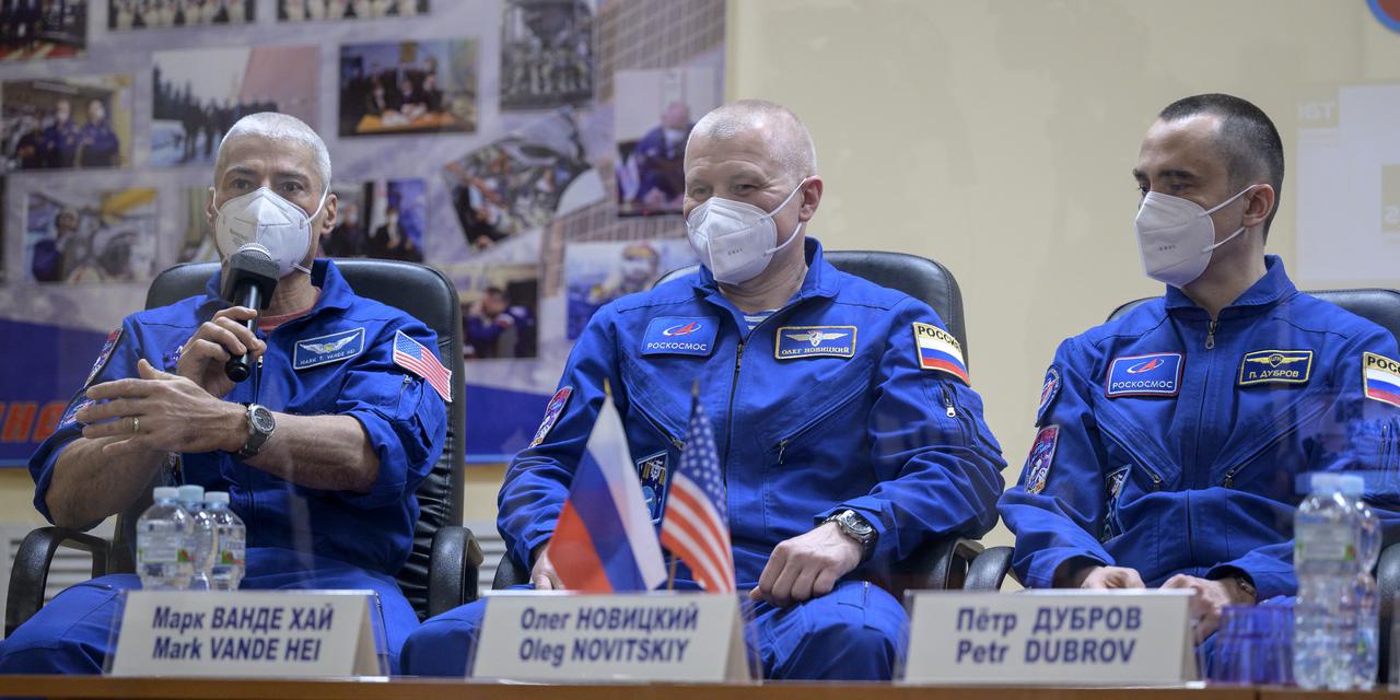 Expedition 65 NASA astronaut Mark Vande Hei, left, Roscosmos cosmonauts Oleg Novitskiy and Pyotr Dubrov, right, are seen in quarantine, behind glass, during a press conference, Thursday, April 8, 2021 a the Cosmonaut Hotel in Baikonur, Kazakhstan. The trio are scheduled to launch to the International Space Station aboard the Soyuz MS-18 spacecraft on April 9.  Photo Credit: (NASA/Bill Ingalls)