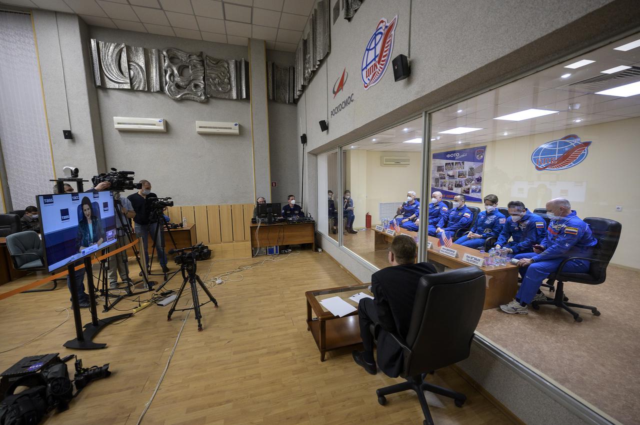 Expedition 65 NASA astronaut Mark Vande Hei, left, Roscosmos cosmonauts Oleg Novitskiy and Pyotr Dubrov, along with backup crew members Anne McClain of NASA, and Roscosmos cosmonauts Anton Shkaplerov and Oleg Artemyev, right, are seen in quarantine, behind glass, during a press conference, Thursday, April 8, 2021 a the Cosmonaut Hotel in Baikonur, Kazakhstan. The prime crew is scheduled to launch to the International Space Station aboard the Soyuz MS-18 spacecraft on April 9.  Photo Credit: (NASA/Bill Ingalls)