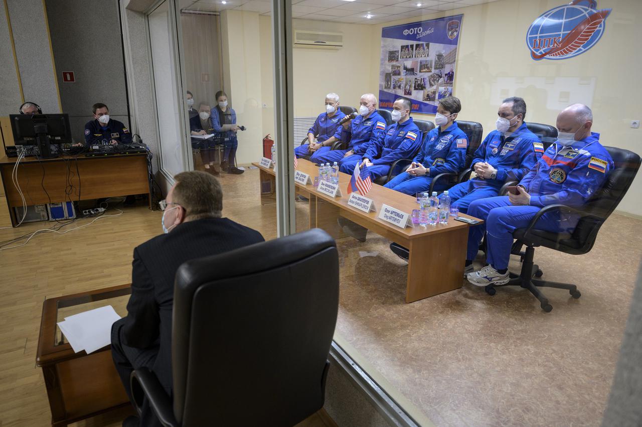 Expedition 65 NASA astronaut Mark Vande Hei, left, Roscosmos cosmonauts Oleg Novitskiy and Pyotr Dubrov, along with backup crew members Anne McClain of NASA, and Roscosmos cosmonauts Anton Shkaplerov and Oleg Artemyev, right, are seen in quarantine, behind glass, during a press conference, Thursday, April 8, 2021 a the Cosmonaut Hotel in Baikonur, Kazakhstan. The prime crew is scheduled to launch to the International Space Station aboard the Soyuz MS-18 spacecraft on April 9.  Photo Credit: (NASA/Bill Ingalls)