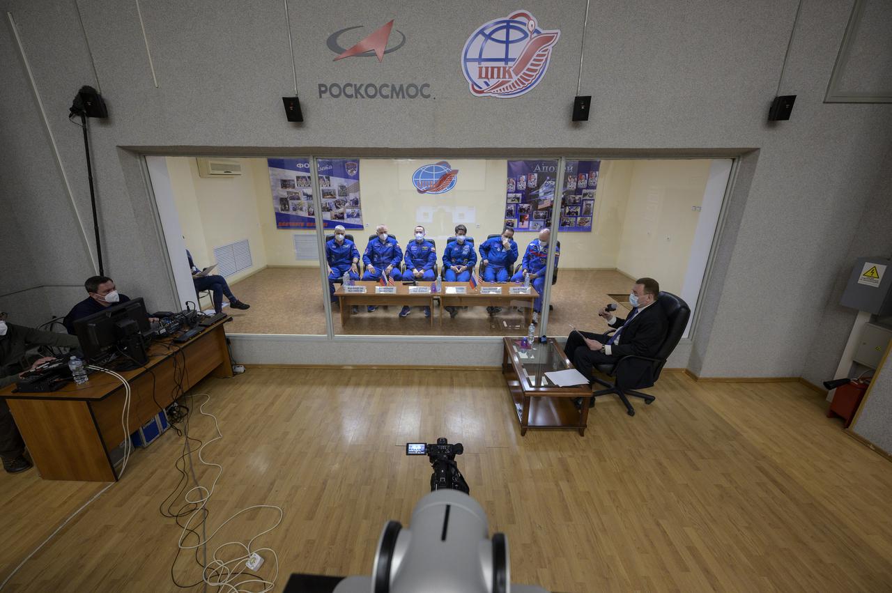 Expedition 65 NASA astronaut Mark Vande Hei, left, Roscosmos cosmonauts Oleg Novitskiy and Pyotr Dubrov, along with backup crew members Anne McClain of NASA, and Roscosmos cosmonauts Anton Shkaplerov and Oleg Artemyev, right, are seen in quarantine, behind glass, during a press conference, Thursday, April 8, 2021 a the Cosmonaut Hotel in Baikonur, Kazakhstan. The prime crew is scheduled to launch to the International Space Station aboard the Soyuz MS-18 spacecraft on April 9.  Photo Credit: (NASA/Bill Ingalls)