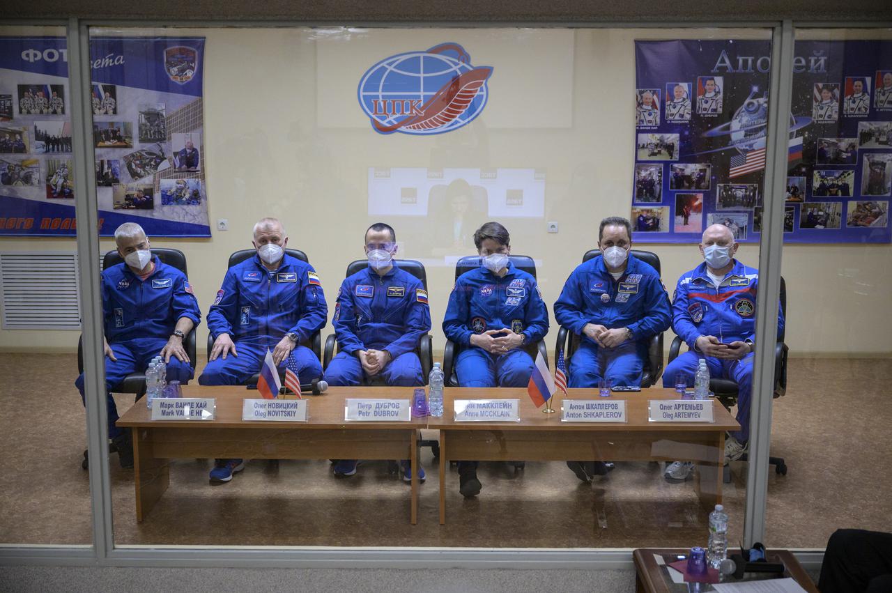 Expedition 65 NASA astronaut Mark Vande Hei, left, Roscosmos cosmonauts Oleg Novitskiy and Pyotr Dubrov, along with backup crew members Anne McClain of NASA, and Roscosmos cosmonauts Anton Shkaplerov and Oleg Artemyev, right, are seen in quarantine, behind glass, during a press conference, Thursday, April 8, 2021 a the Cosmonaut Hotel in Baikonur, Kazakhstan. The prime crew is scheduled to launch to the International Space Station aboard the Soyuz MS-18 spacecraft on April 9.  Photo Credit: (NASA/Bill Ingalls)