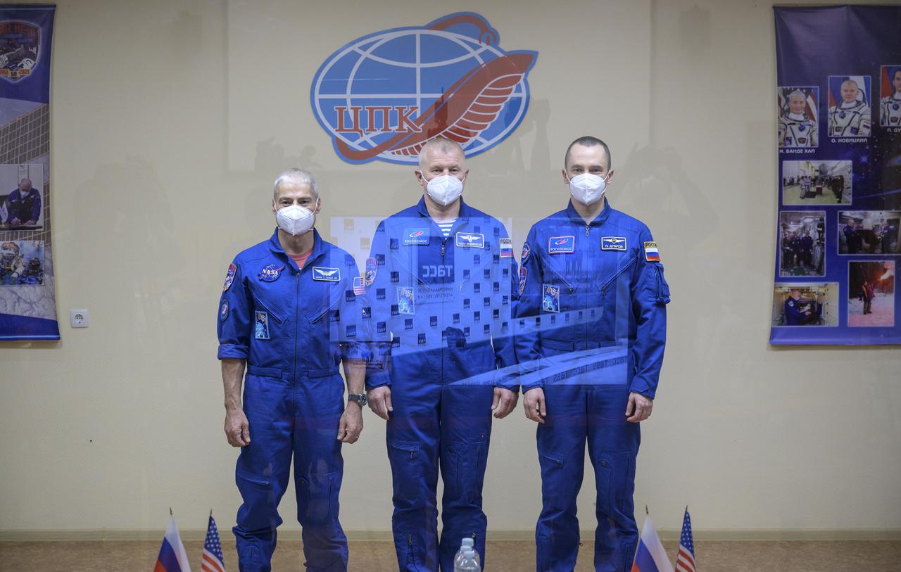 Expedition 65 NASA astronaut Mark Vande Hei, left, Roscosmos cosmonauts Oleg Novitskiy and Pyotr Dubrov, right, are seen in quarantine, behind glass, during a press conference, Thursday, April 8, 2021 a the Cosmonaut Hotel in Baikonur, Kazakhstan. The trio is scheduled to launch to the International Space Station aboard the Soyuz MS-18 spacecraft on April 9.  Photo Credit: (NASA/Bill Ingalls)