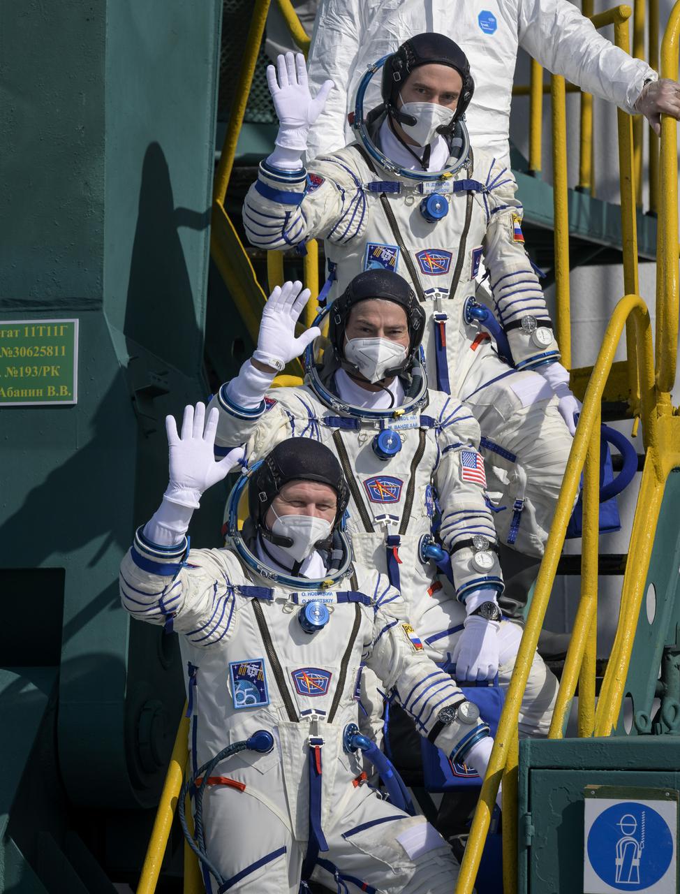 Expedition 65 Russian cosmonaut Pyotr Dubrov, top, NASA astronaut Mark Vande Hei, middle, and Russian cosmonaut Oleg Novitskiy wave farewell prior to boarding the Soyuz MS-18 spacecraft for launch, Friday, April 9, 2021 at the Baikonur Cosmodrome in Kazakhstan. Launch of the Soyuz rocket will send the trio on a mission to the International Space Station. Photo Credit: (NASA/Bill Ingalls)