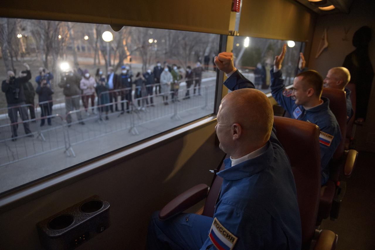 Expedition 65 Roscosmos cosmonauts Oleg Novitskiy , left, Pyotr Dubrov, center, and NASA astronaut Mark Vande Hei, wave as they depart the Cosmonaut Hotel to suit-up for their Soyuz launch to the International Space Station, Friday, April 9, 2021, in Baikonur, Kazakhstan. Later that same day the crew launched in their Soyuz MS-18 spacecraft to the International Space Station. Photo Credit: (NASA/GCTC/Irina Spector