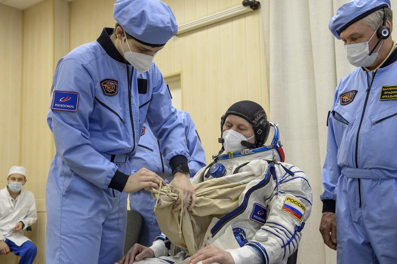 Expedition 65 Russian cosmonaut Oleg Novitskiy is helped into his Russian Sokol suit as he and fellow crewmates, prepare for their Soyuz launch to the International Space Station Friday, April 9, 2021 in Baikonur, Kazakhstan. Launch of the Soyuz rocket will sent Novitskiy, Russian cosmonaut Pyotr Dubrov and NASA astronaut Mark Vande Hei on a mission to the International Space Station. Photo Credit: (NASA/GCTC/Irina Spector)