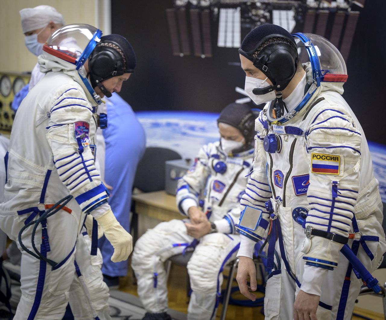 Expedition 65 Russian cosmonaut Oleg Novitskiy, left, NASA astronaut Mark Vande Hei, center, and  Russian cosmonaut Pyotr Dubrov prepare their Russian Sokol suits for their Soyuz launch to the International Space Station Friday, April 9, 2021 in Baikonur, Kazakhstan. Launch of the Soyuz rocket sent the trio on a mission to the International Space Station. Photo Credit: (NASA/Bill Ingalls)