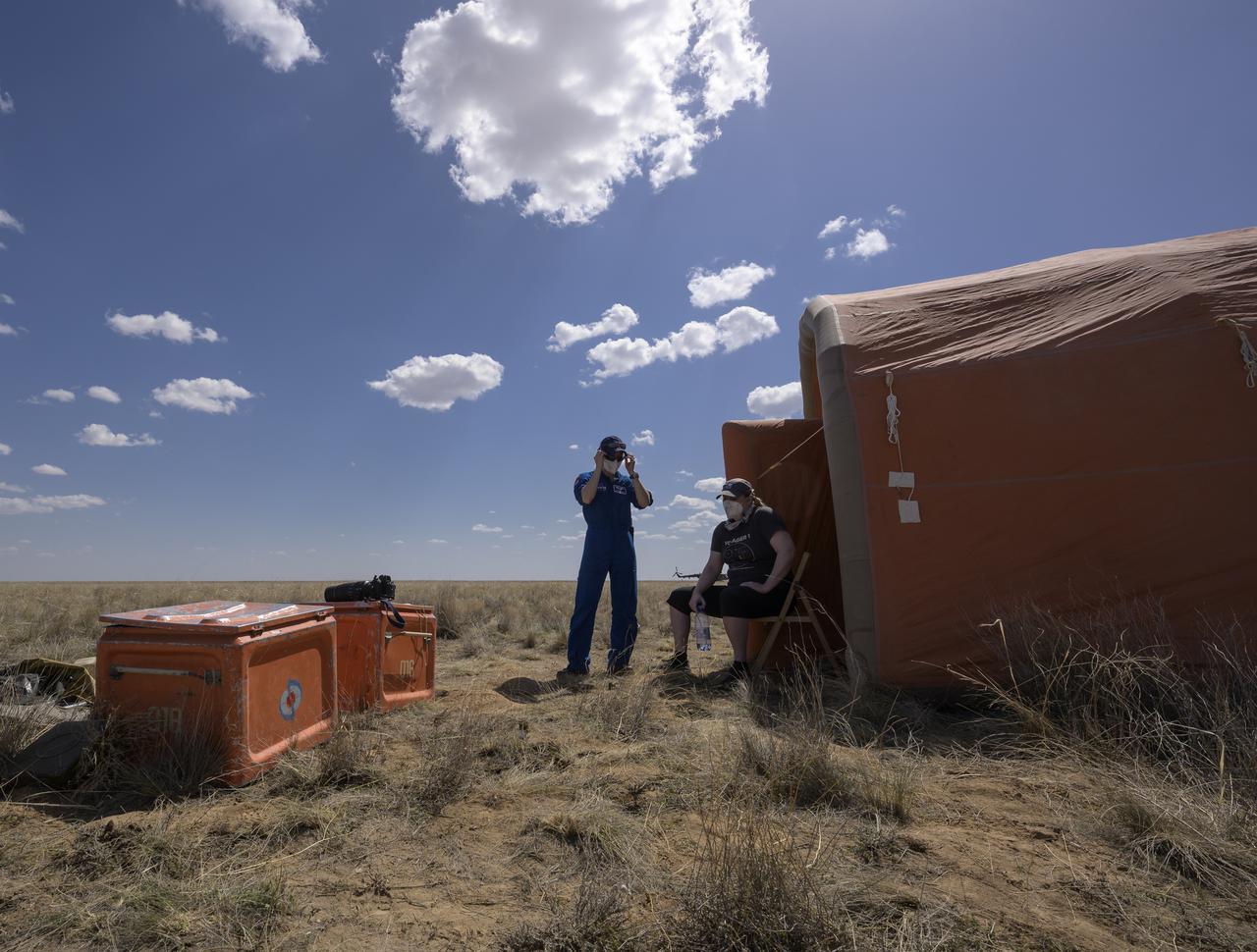 Expedition 64 NASA astronaut Kate Rubins, seated, and NASA Flight Surgeon Natacha Chough enjoy some fresh air outside the medical tent shortly after Rubins, and Roscosmos cosmonauts Sergey Ryzhikov and Sergey Kud-Sverchkov landed in their Soyuz MS-17 spacecraft near the town of Zhezkazgan, Kazakhstan on Saturday, April 17, 2021. Rubins, Ryzhikov and Kud-Sverchkov returned after 185 days in space having served as Expedition 63-64 crew members onboard the International Space Station. Photo Credit: NASA/Bill Ingalls