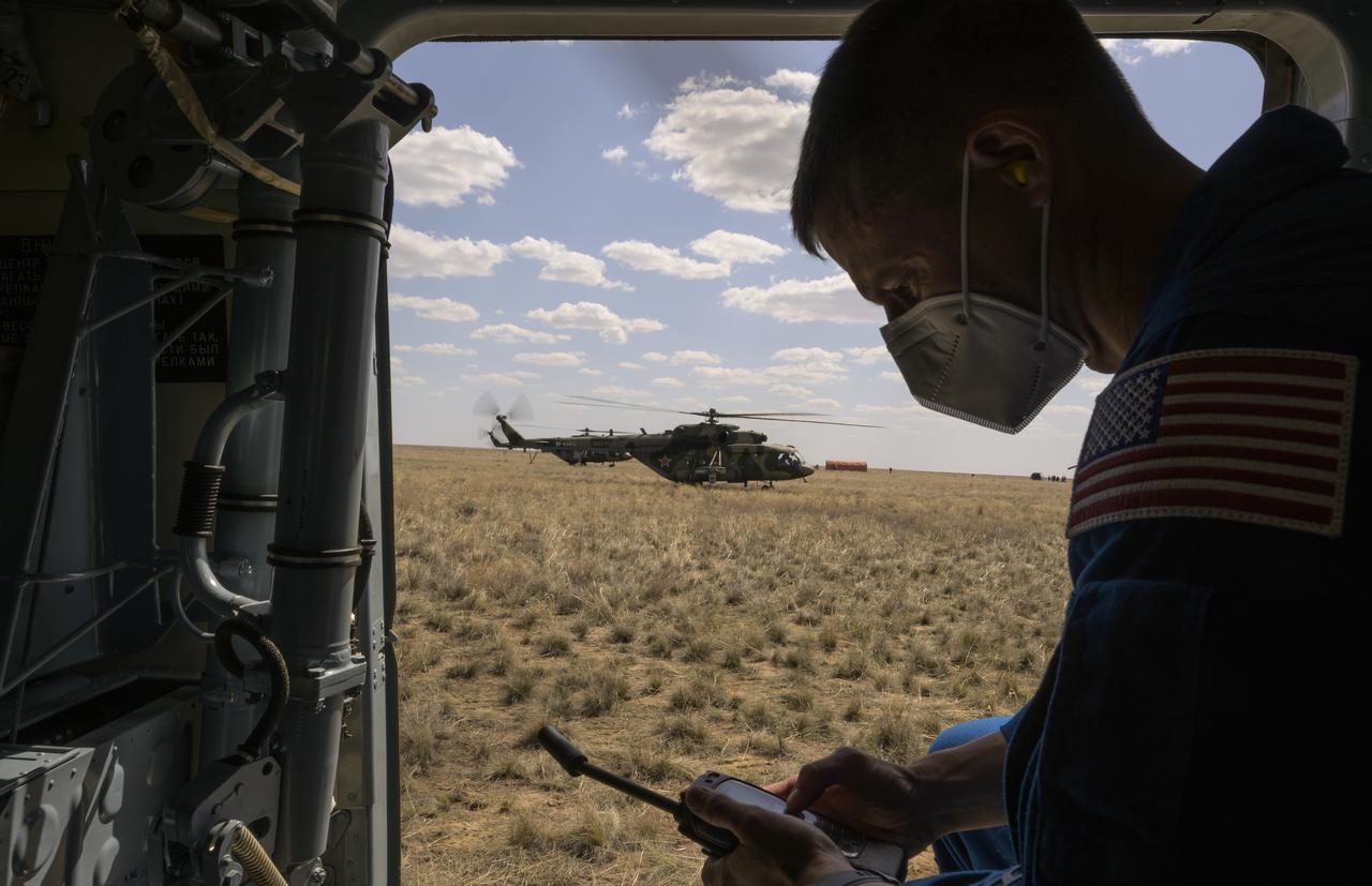 NASA Astronaut Office Representative and astronaut Drew Morgan communicates back to Houston of the status of NASA astronaut Kate Rubins while onboard a Russian MI-8 helicopter that will them to Karaganda after Rubins, and Roscosmos cosmonauts Sergey Ryzhikov and Sergey Kud-Sverchkov, landed in their Soyuz MS-17 spacecraft near the town of Zhezkazgan, Kazakhstan on Saturday, April 17, 2021. Rubins, Ryzhikov and Kud-Sverchkov returned after 185 days in space having served as Expedition 63-64 crew members onboard the International Space Station. Photo Credit: NASA/Bill Ingalls
