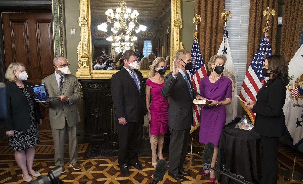 Former Senator Bill Nelson, is ceremonially sworn-in as the 14th NASA Administrator by Vice President Kamala Harris, as his wife, Grace Nelson, holds their family Bible, and son, Bill Nelson Jr., third from left, and Nan Ellen Nelson, fourth from left, look on, Monday, May 3, 2021, at the Ceremonial Office in the Old Executive Office Building in Washington. A moon rock collected by astronaut John Young during the Apollo 16 mission was on display and former NASA Administrators Jim Bridenstine (virtually on laptop) and Charles Bolden, second from left, as well as Pam Melroy, current nominee for NASA Deputy Administrator, left, were also present. Photo Credit: (NASA/Aubrey Gemignani)