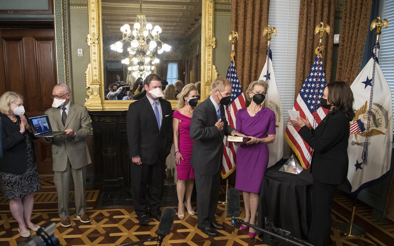 Former Senator Bill Nelson, is ceremonially sworn-in as the 14th NASA Administrator by Vice President Kamala Harris, as his wife, Grace Nelson, holds their family Bible, and son, Bill Nelson Jr., third from left, and Nan Ellen Nelson, fourth from left, look on, Monday, May 3, 2021, at the Ceremonial Office in the Old Executive Office Building in Washington. A moon rock collected by astronaut John Young during the Apollo 16 mission was on display and former NASA Administrators Jim Bridenstine (virtually on laptop) and Charles Bolden, second from left, as well as Pam Melroy, current nominee for NASA Deputy Administrator, left, were also present. Photo Credit: (NASA/Aubrey Gemignani)