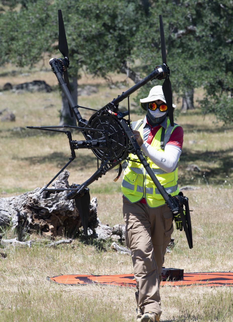Jonas Jonsson, pilot in command for STEReO, the Scalable Traffic Management for Emergency Response Operations project, at NASA's Ames Research Center, is seen moving a FreeFly Systems Alta X drone following a flight during STEReO, the Scalable Traffic Management for Emergency Response Operations project, test activities, Tuesday, May 4, 2021 as Cal Fire conducts aerial fire fighting training exercises near Redding, California. STEReO, the Scalable Traffic Management for Emergency Response Operations project, led by NASA’s Ames Research Center, builds on NASA’s expertise in air traffic management, human factors research, and autonomous technology development to apply the agency’s work in Unmanned Aircraft Systems Traffic Management, or UTM, to public safety uses. Photo Credit: (NASA/Joel Kowsky)