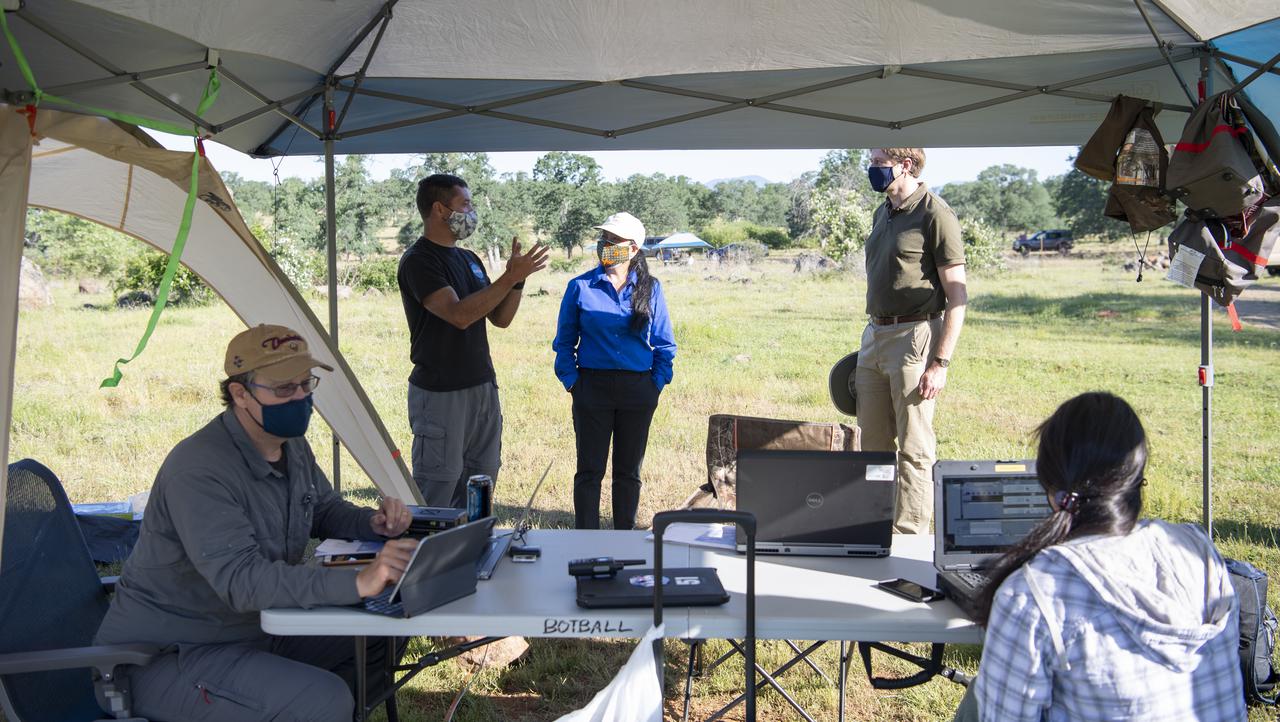 George Lawton, system architect for STEReO, the Scalable Traffic Management for Emergency Response Operations project, at NASA's Ames Research Center, seated left, and Yasmin Arbab, human factors researcher and research laptop operator for STEReO at NASA's Ames Research Center, seated right, are seen as Joey Mercer, principle investigator for STEReO at NASA's Ames Research Center, standing left, speaks with Huy Tran, director of aeronautics at NASA's Ames Research Center, center, and Richard Barhydt, station director of the U.S. Forest Service's Pacific Southwest Research Station, right, during STEReO test activities, Tuesday, May 4, 2021 as Cal Fire conducts aerial fire fighting training exercises near Redding, California. STEReO, the Scalable Traffic Management for Emergency Response Operations project, led by NASA’s Ames Research Center, builds on NASA’s expertise in air traffic management, human factors research, and autonomous technology development to apply the agency’s work in Unmanned Aircraft Systems Traffic Management, or UTM, to public safety uses. Photo Credit: (NASA/Joel Kowsky)