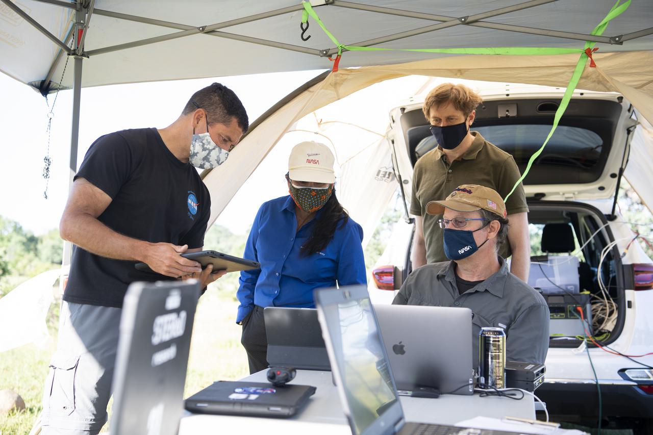 Joey Mercer, principle investigator for STEReO, the Scalable Traffic Management for Emergency Response Operations project, at NASA's Ames Research Center, left, Huy Tran, director of aeronautics at NASA's Ames Research Center, center, and Richard Barhydt, station director of the U.S. Forest Service's Pacific Southwest Research Station, standing right, speak with George Lawton, system architect for STEReO at NASA's Ames Research Center, seated right, during STEReO test activities, Tuesday, May 4, 2021 as Cal Fire conducts aerial fire fighting training exercises near Redding, California. STEReO, the Scalable Traffic Management for Emergency Response Operations project, led by NASA’s Ames Research Center, builds on NASA’s expertise in air traffic management, human factors research, and autonomous technology development to apply the agency’s work in Unmanned Aircraft Systems Traffic Management, or UTM, to public safety uses. Photo Credit: (NASA/Joel Kowsky)