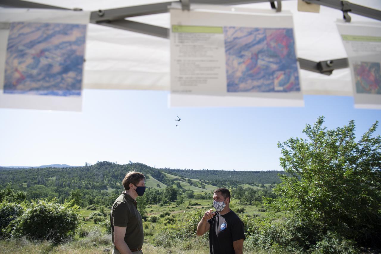 Joey Mercer, principle investigator for STEReO, the Scalable Traffic Management for Emergency Response Operations project, at NASA's Ames Research Center , right, speaks with Richard Barhydt, station director of the U.S. Forest Service's Pacific Southwest Research Station, left, during STEReO test activities, Tuesday, May 4, 2021 as Cal Fire conducts aerial fire fighting training exercises near Redding, California. STEReO, the Scalable Traffic Management for Emergency Response Operations project, led by NASA’s Ames Research Center, builds on NASA’s expertise in air traffic management, human factors research, and autonomous technology development to apply the agency’s work in Unmanned Aircraft Systems Traffic Management, or UTM, to public safety uses. Photo Credit: (NASA/Joel Kowsky)