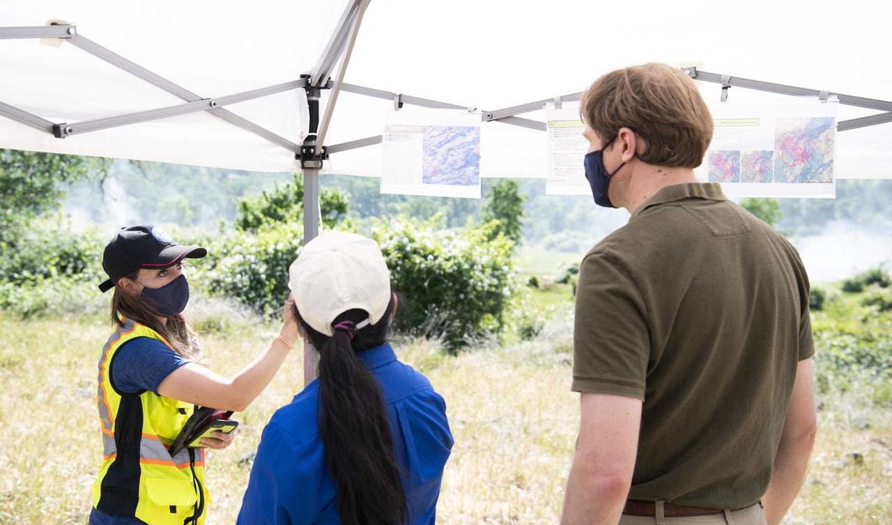 Lauren Claudatos, researcher for STEReO, the Scalable Traffic Management for Emergency Response Operations project, at NASA's Ames Research Center, right, speaks with Richard Barhydt, station director of the U.S. Forest Service's Pacific Southwest Research Station, left, and Huy Tran, director of aeronautics at NASA's Ames Research Center, center, during STEReO test activities, Tuesday, May 4, 2021 as Cal Fire conducts aerial fire fighting training exercises near Redding, California. STEReO, the Scalable Traffic Management for Emergency Response Operations project, led by NASA’s Ames Research Center, builds on NASA’s expertise in air traffic management, human factors research, and autonomous technology development to apply the agency’s work in Unmanned Aircraft Systems Traffic Management, or UTM, to public safety uses. Photo Credit: (NASA/Joel Kowsky)