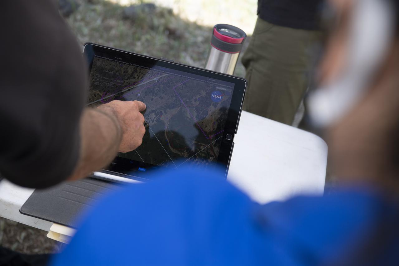 Joey Mercer, principle investigator for STEReO, the Scalable Traffic Management for Emergency Response Operations project, at NASA's Ames Research Center, points to a location on a tablet running a version of theUnmanned Aircraft Systems Traffic Management System (UTM) during STEReO field testing, Tuesday, May 4, 2021 as Cal Fire conducts aerial fire fighting training exercises near Redding, California.  STEReO, the Scalable Traffic Management for Emergency Response Operations project, led by NASA’s Ames Research Center, builds on NASA’s expertise in air traffic management, human factors research, and autonomous technology development to apply the agency’s work in Unmanned Aircraft Systems Traffic Management, or UTM, to public safety uses. Photo Credit: (NASA/Joel Kowsky)