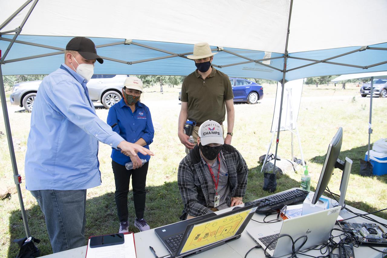 Robert McSwain, co-principle investigator and autonomy researcher for STEReO, the Scalable Traffic Management for Emergency Response Operations project, at NASA's Langley Research Center, left, speaks with Huy Tran, director of aeronautics at NASA's Ames Research Center, center, and Richard Barhydt, station director of the U.S. Forest Service's Pacific Southwest Research Station, right, during STEReO test activities, Tuesday, May 4, 2021 as Cal Fire conducts aerial fire fighting training exercises near Redding, California. STEReO, the Scalable Traffic Management for Emergency Response Operations project, led by NASA’s Ames Research Center, builds on NASA’s expertise in air traffic management, human factors research, and autonomous technology development to apply the agency’s work in Unmanned Aircraft Systems Traffic Management, or UTM, to public safety uses. Photo Credit: (NASA/Joel Kowsky)