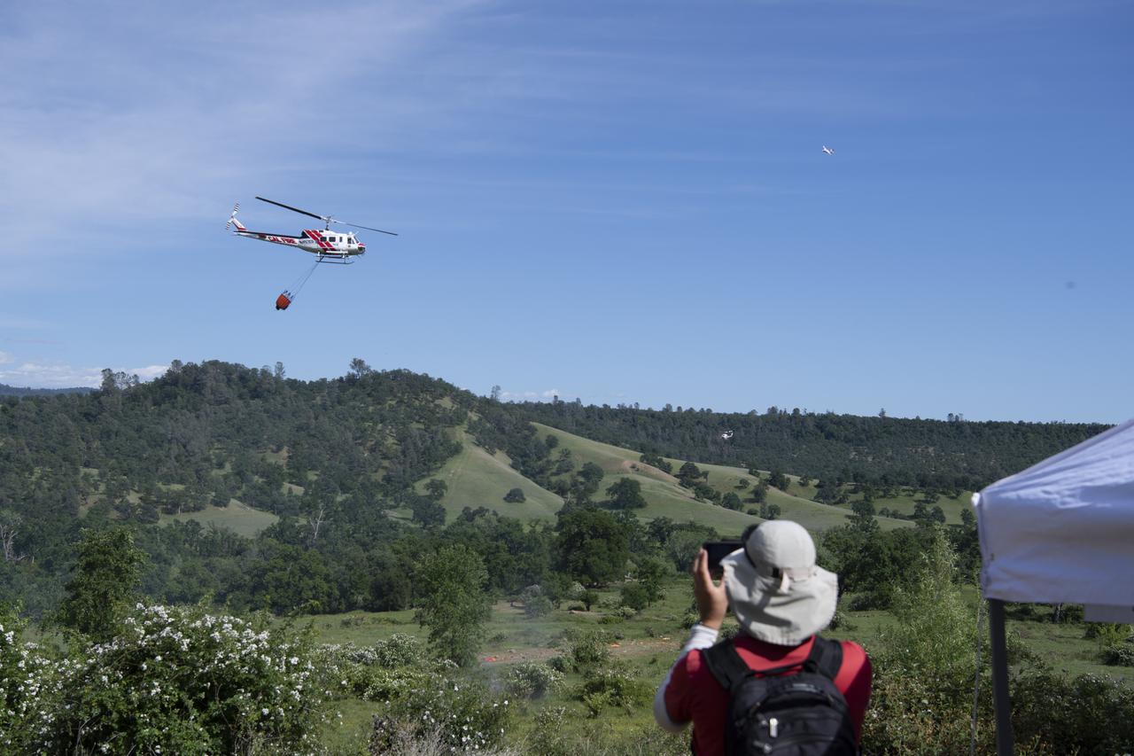 A Cal Fire UH-1H Super Huey helicopter is seen in flight as a member of the STEReO, the Scalable Traffic Management for Emergency Response Operations project team watches, Tuesday, May 4, 2021, as Cal Fire conducts aerial fire fighting training exercises near Redding, California.  STEReO, the Scalable Traffic Management for Emergency Response Operations project, led by NASA’s Ames Research Center, builds on NASA’s expertise in air traffic management, human factors research, and autonomous technology development to apply the agency’s work in Unmanned Aircraft Systems Traffic Management, or UTM, to public safety uses. Photo Credit: (NASA/Joel Kowsky)
