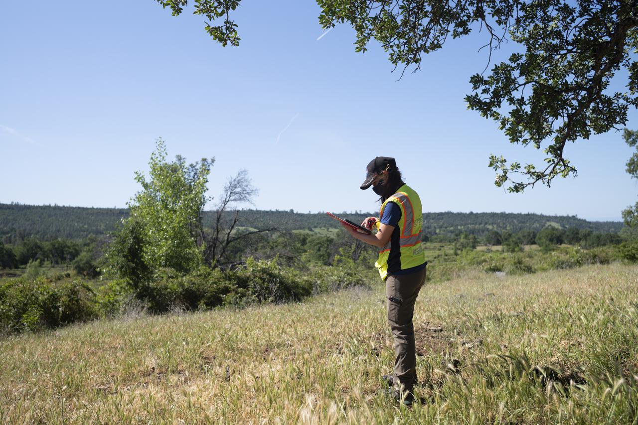 Lauren Claudatos, researcher for STEReO, the Scalable Traffic Management for Emergency Response Operations project, at NASA's Ames Research Center, is seen during simulated drone operations during STEReO field testing, Tuesday, May 4, 2021 as Cal Fire conducts aerial fire fighting training exercises near Redding, California.  STEReO, the Scalable Traffic Management for Emergency Response Operations project, led by NASA’s Ames Research Center, builds on NASA’s expertise in air traffic management, human factors research, and autonomous technology development to apply the agency’s work in Unmanned Aircraft Systems Traffic Management, or UTM, to public safety uses. Photo Credit: (NASA/Joel Kowsky)