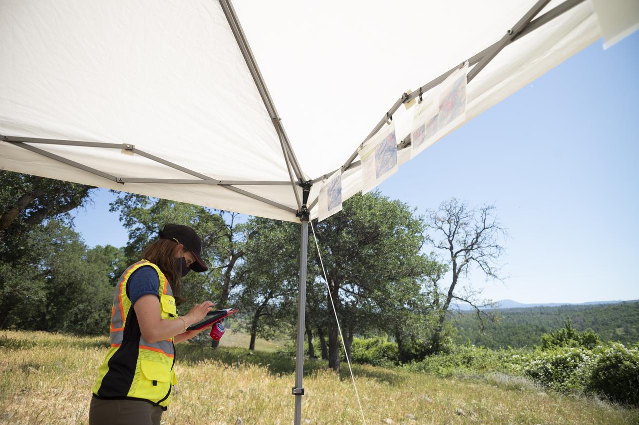 Lauren Claudatos, researcher for STEReO, the Scalable Traffic Management for Emergency Response Operations project, at NASA's Ames Research Center, is seen during simulated drone operations during STEReO field testing, Tuesday, May 4, 2021 as Cal Fire conducts aerial fire fighting training exercises near Redding, California.  STEReO, the Scalable Traffic Management for Emergency Response Operations project, led by NASA’s Ames Research Center, builds on NASA’s expertise in air traffic management, human factors research, and autonomous technology development to apply the agency’s work in Unmanned Aircraft Systems Traffic Management, or UTM, to public safety uses. Photo Credit: (NASA/Joel Kowsky)